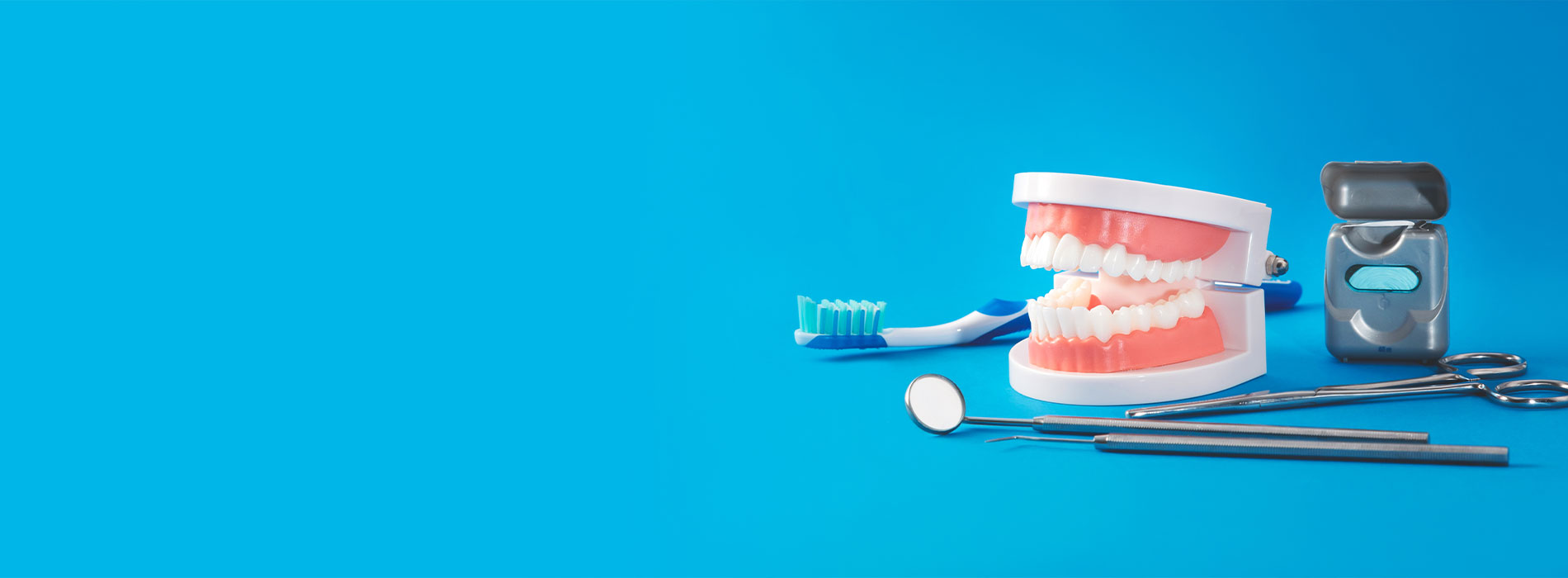 The image shows a collection of dental tools and equipment, including toothbrushes and a dental mirror, laid out on a blue surface with a focus on oral hygiene.