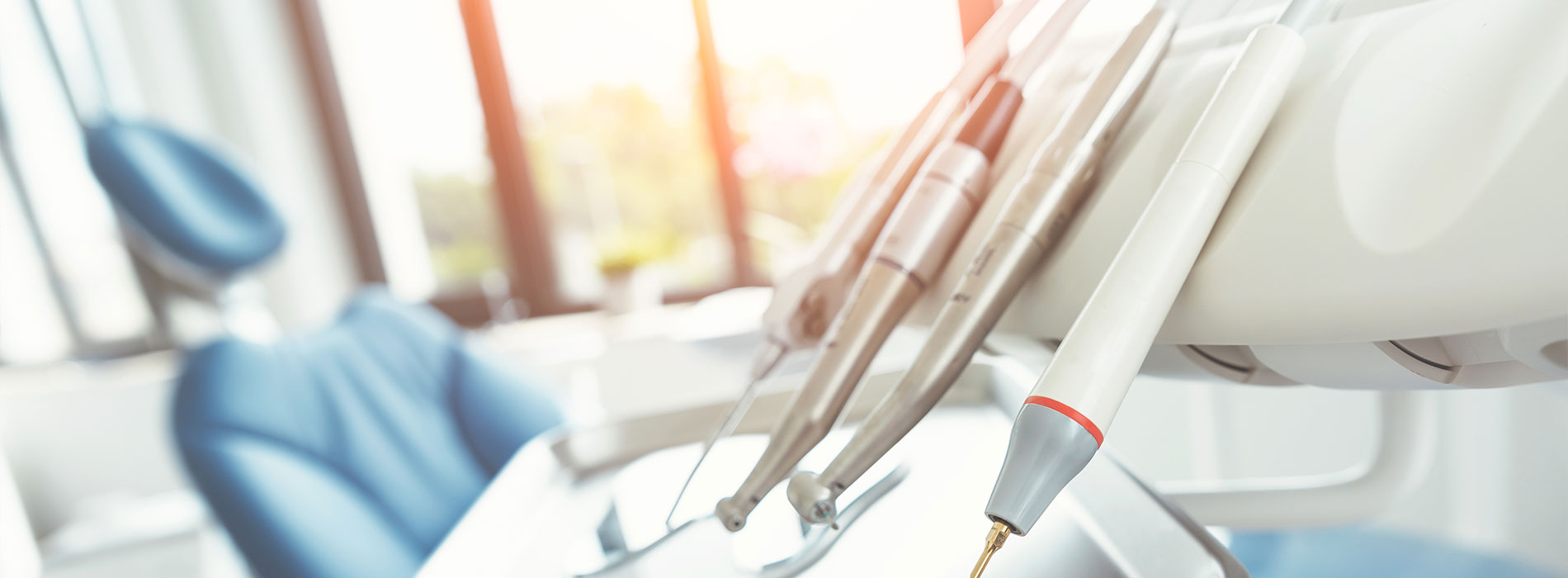 The image shows a modern dental clinic interior with various pieces of equipment, including a dental chair and an X-ray machine.