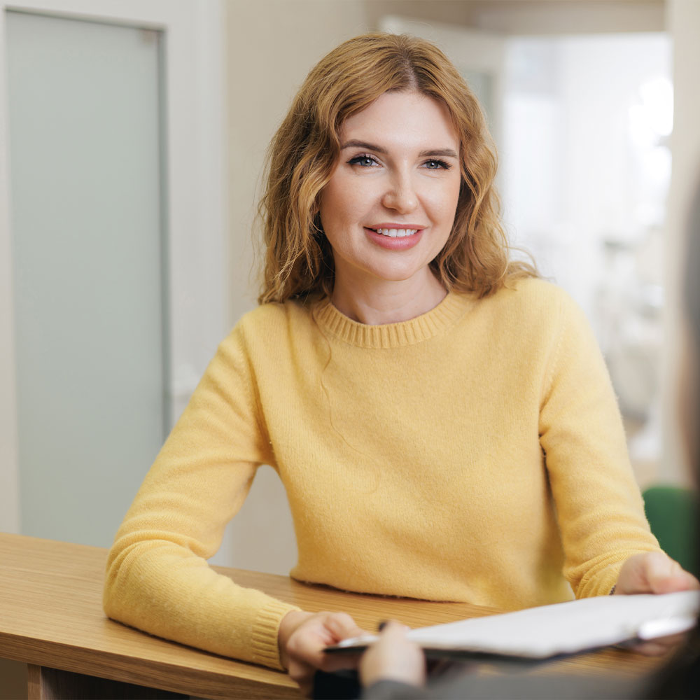 The image shows a modern office space with a sleek desk, chair, and computer setup, featuring wood paneling, a white countertop, and a contemporary design.