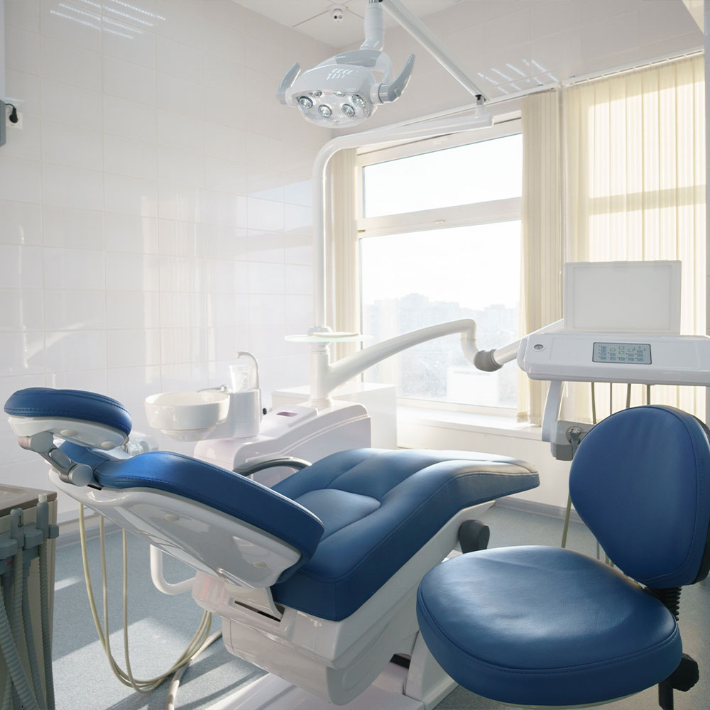 The image shows a dental office interior with a dental chair, a dental light, and various dental equipment.